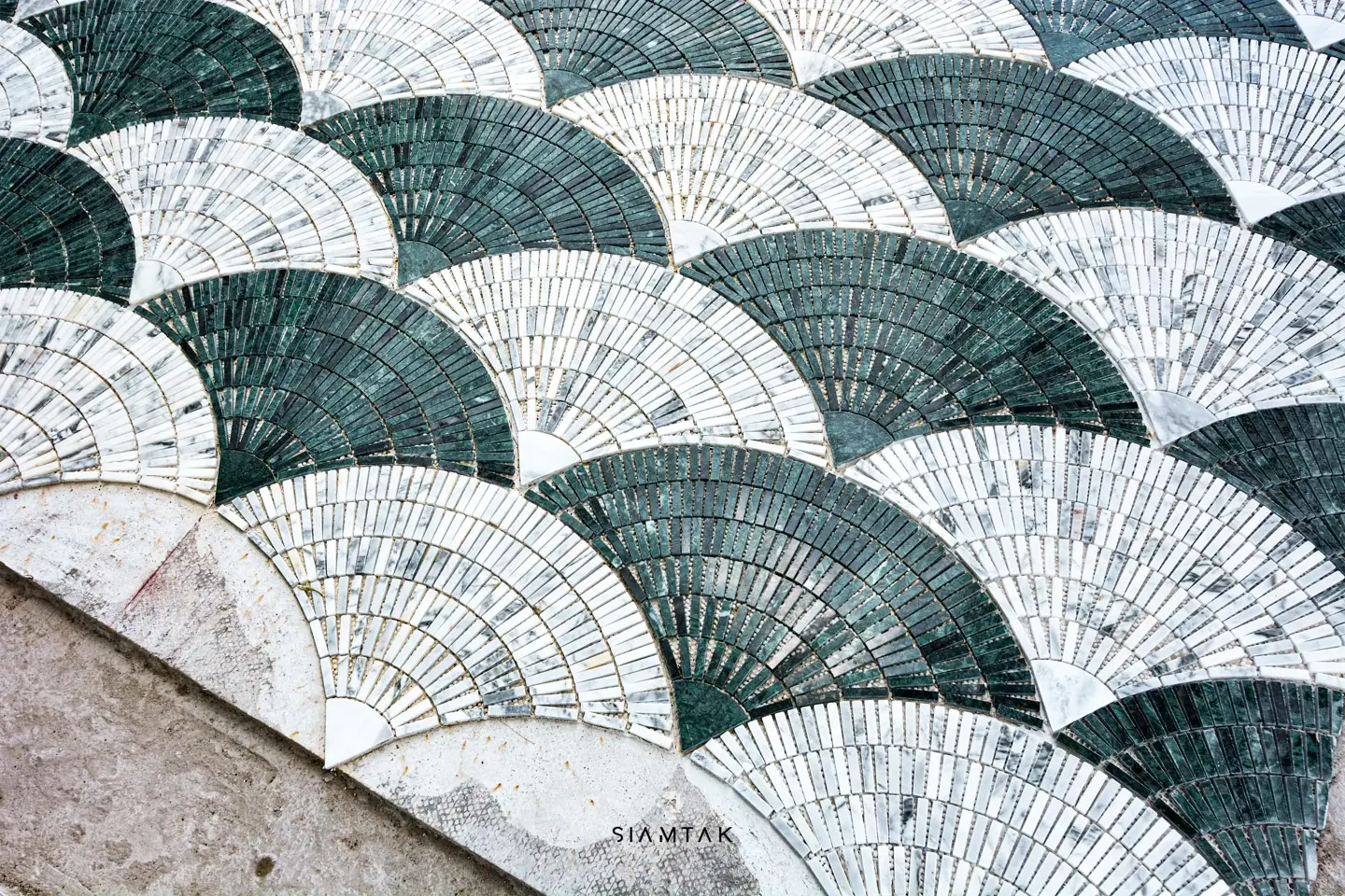 White Carrara and Rajasthan Green marble are used to create a propeller-patterned mosaic tile floor