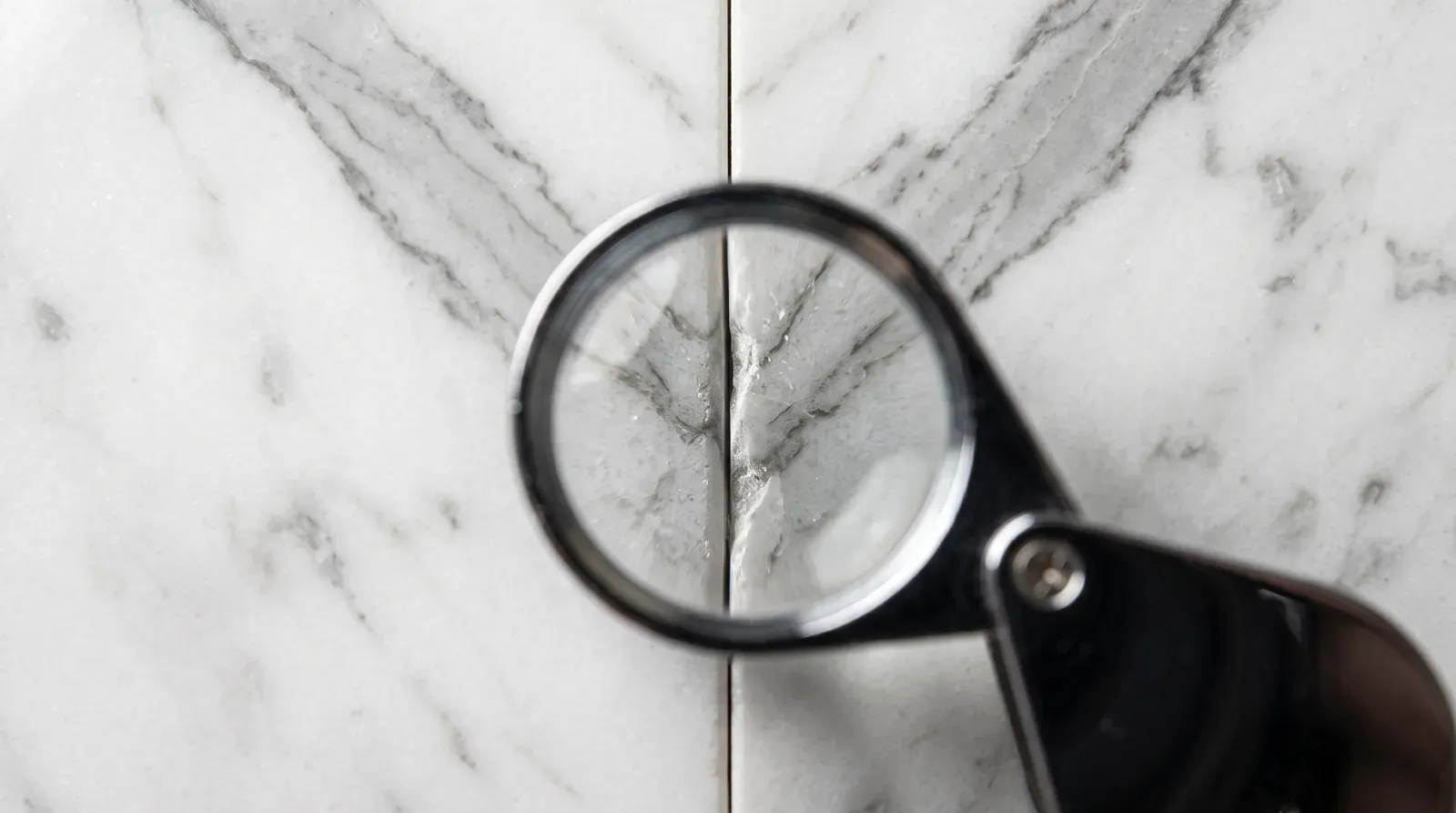 Magnifying glass over the joint between marble slabs whose veins do not align with mathematical precision